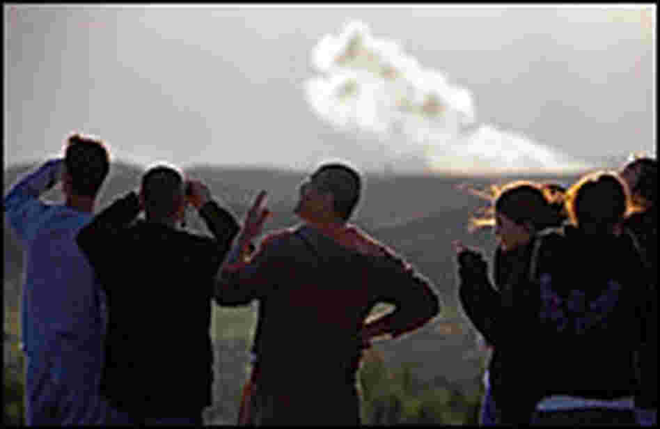 Residents of Sderot and visitors gather on a hilltop to watch Israeli airstrikes in the distance