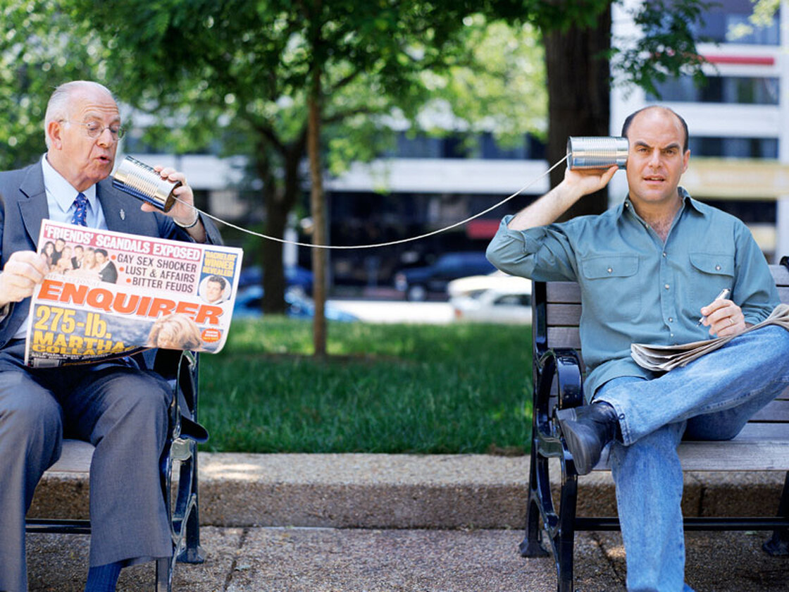 Carl Kasell and Peter Sagal talk on a tin-can phone.