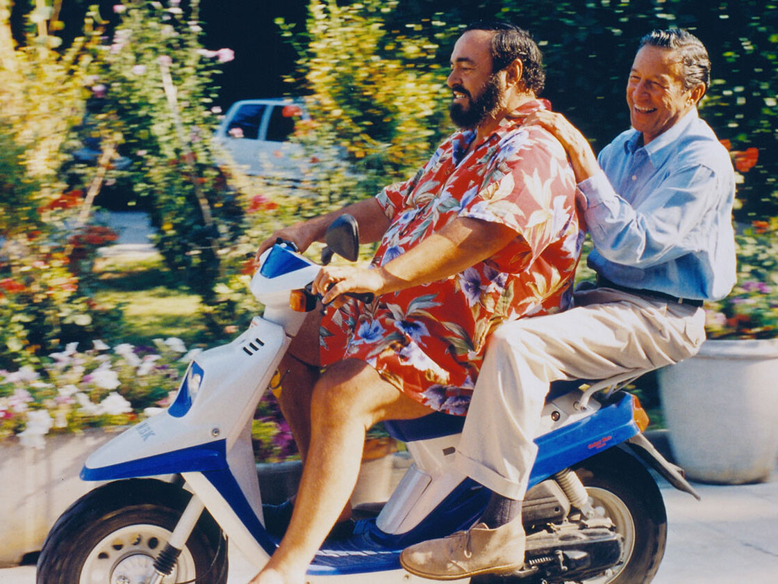 Correspondent Mike Wallace gets a lift from Luciano Pavarotti in 1993.