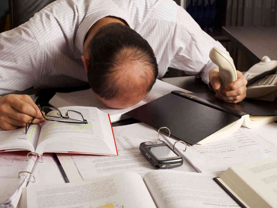 Man surrounded by paper and digital gadgets