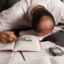 Man surrounded by paper and digital gadgets