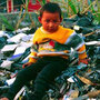 migrant child sits atop a pile of unrecyclable computer waste imported to Guiya, China, from other countries.