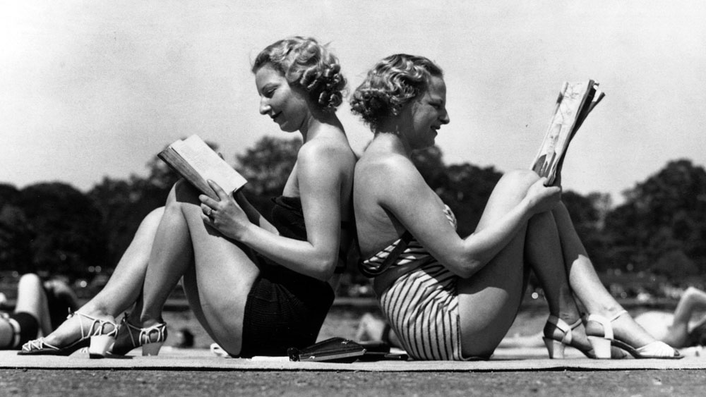 Two women reading back to back as they sunbathe in Hyde Park, London in May 1937.