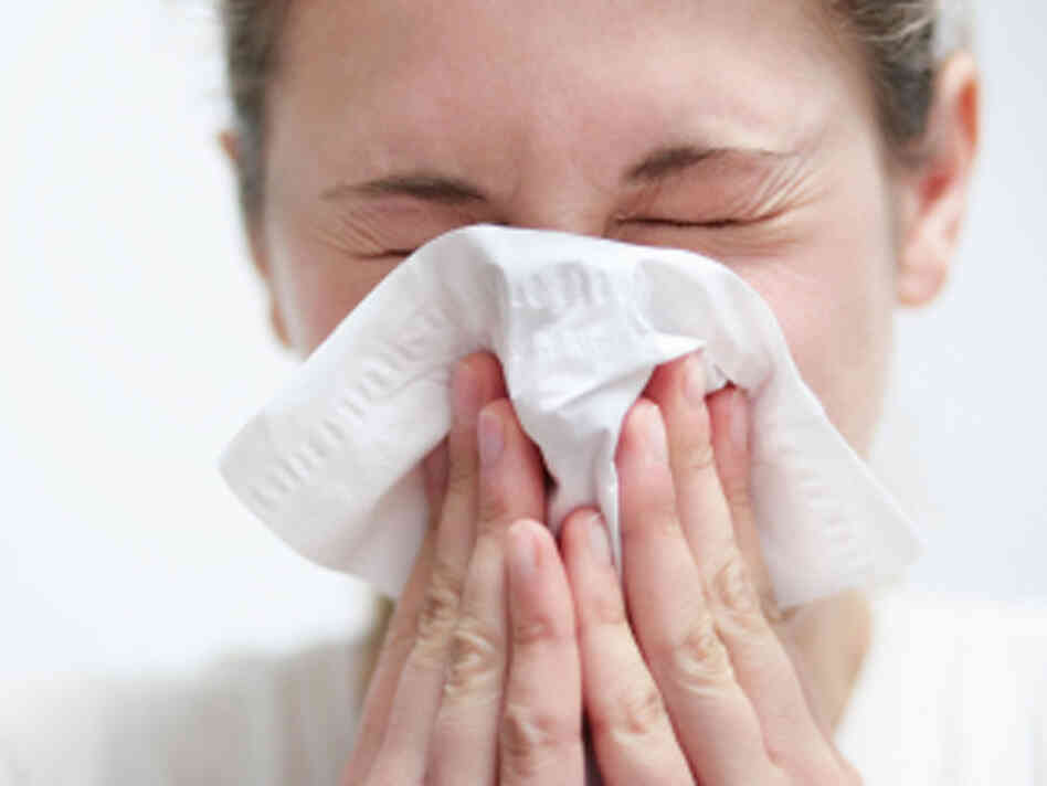 A woman sneezing into a tissue