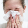 A woman sneezing into a tissue