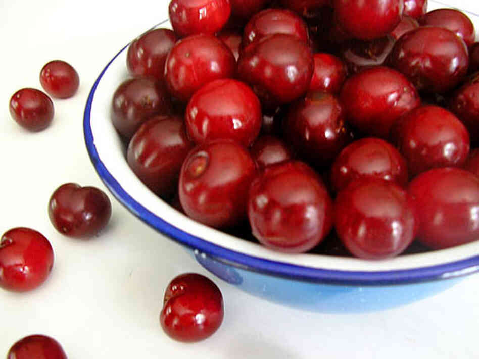 A blue-rimmed bowl overflowing with deep red sour cherries
