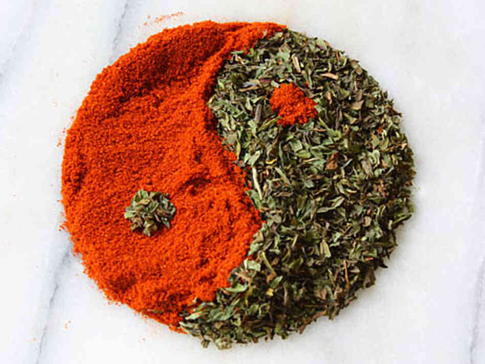 A yin and yang of red powdered paprika and green flaky dried mint