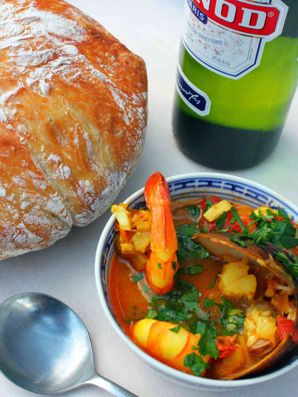 Bowl of bouillabaisse, brimming with seafood, served with Pernod and loaf of crusty bread Bowl of bouillabaisse, brimming with seafood, served with Pernod and loaf of crusty bread
