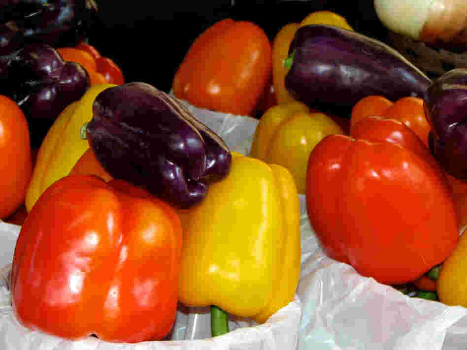 Red, purple and yellow peppers fill bags at a farmers market