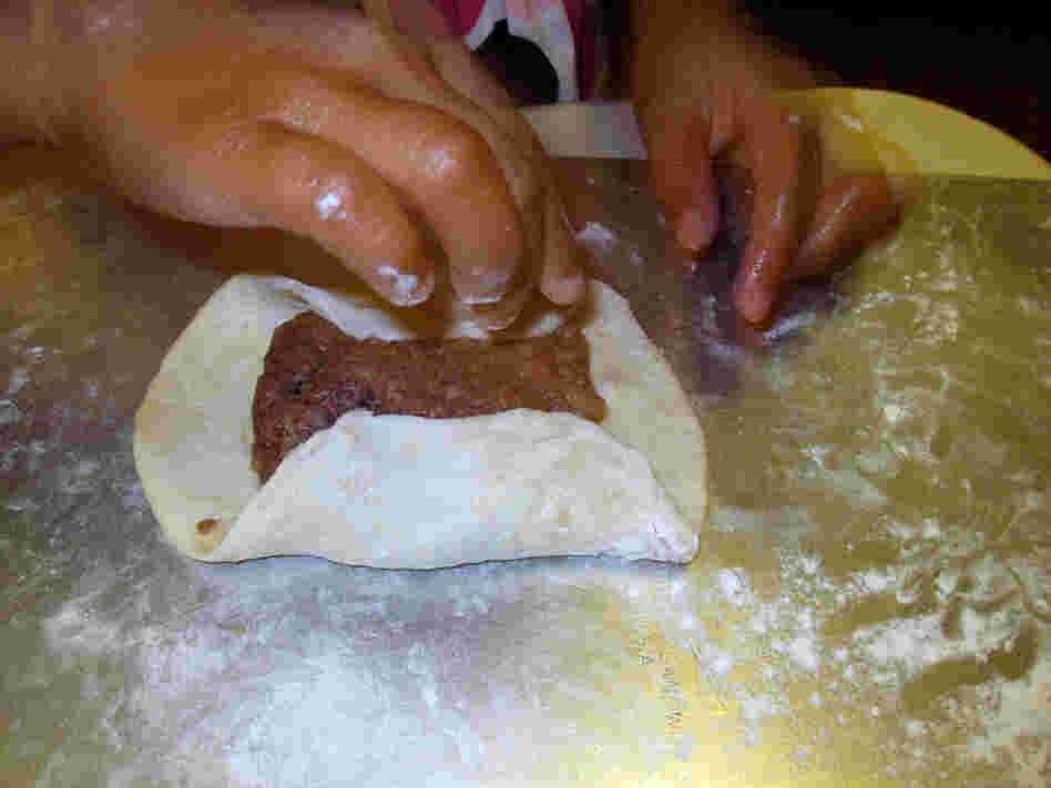 The hands of Michele Kayal's daughter manipulate a meat pie