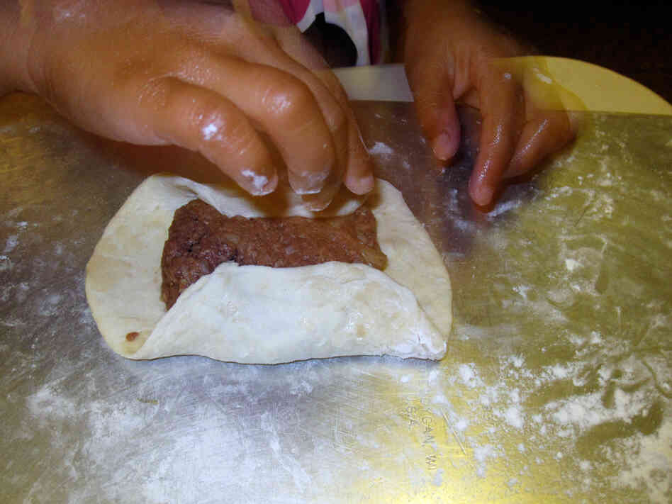 The hands of Michele Kayal's daughter manipulate a meat pie