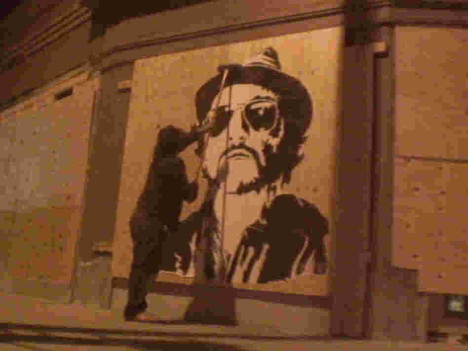 Banksy putting one of his pieces up on a wall in London