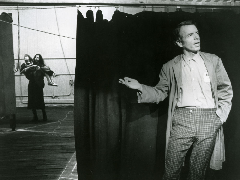 Spalding Gray by a stage curtain