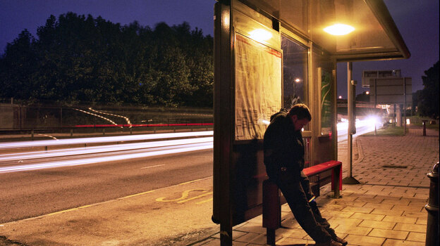 A man waits at a bus stop.