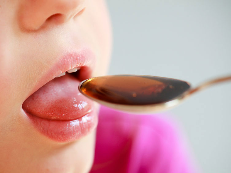 A child takes liquid medicine.