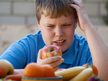 an overweight boy eyes fruit.