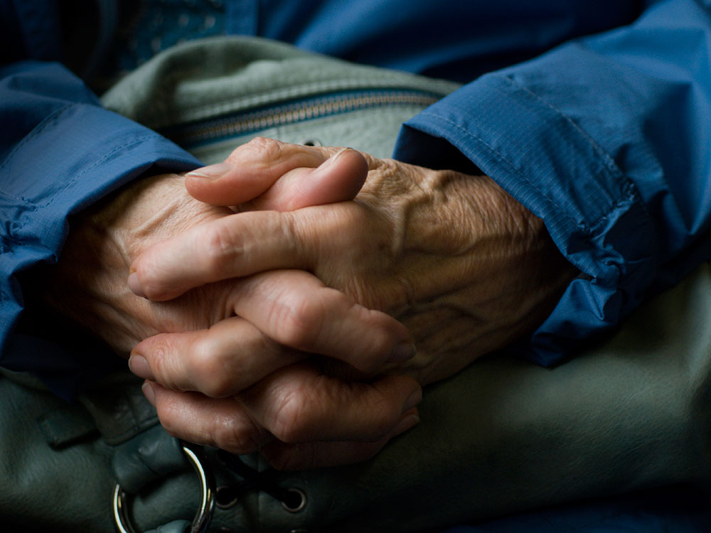 An old person folds hands.