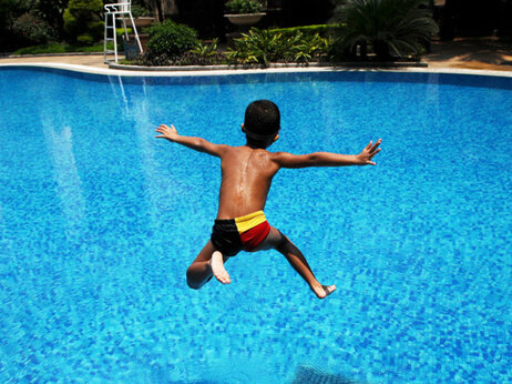 A boy jumps into a swimming pool.