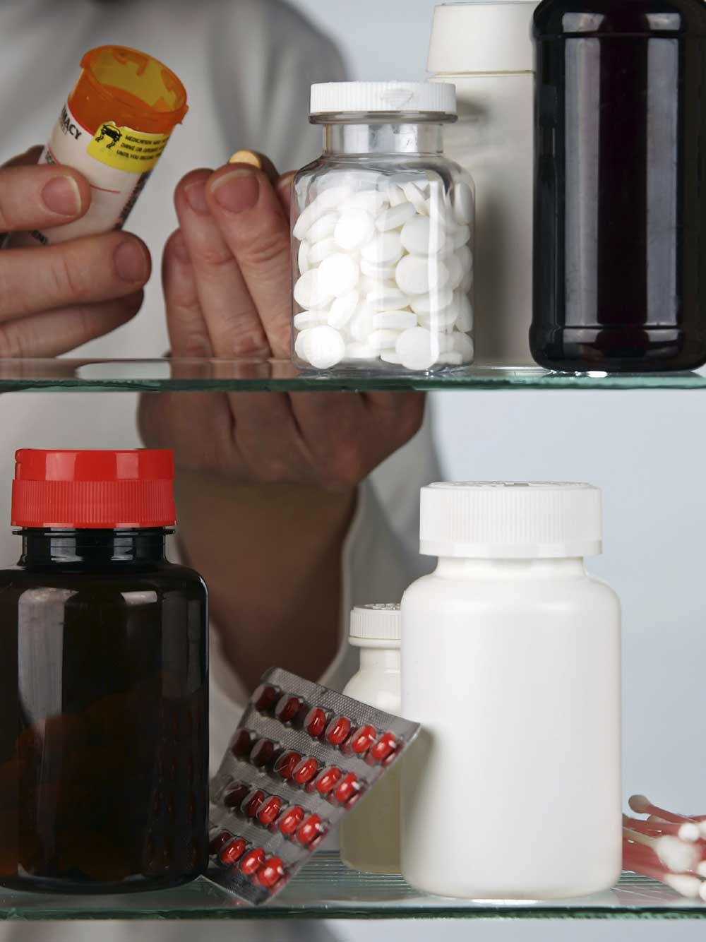 Person checks expiration dates on drugs in a medicine cabinet.