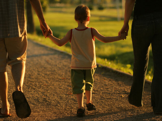 Young child walks with his parents.