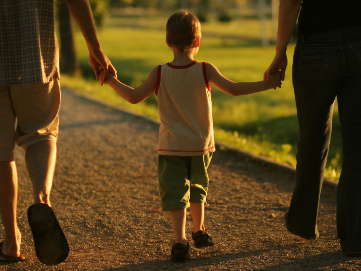 Young child walks with his parents.