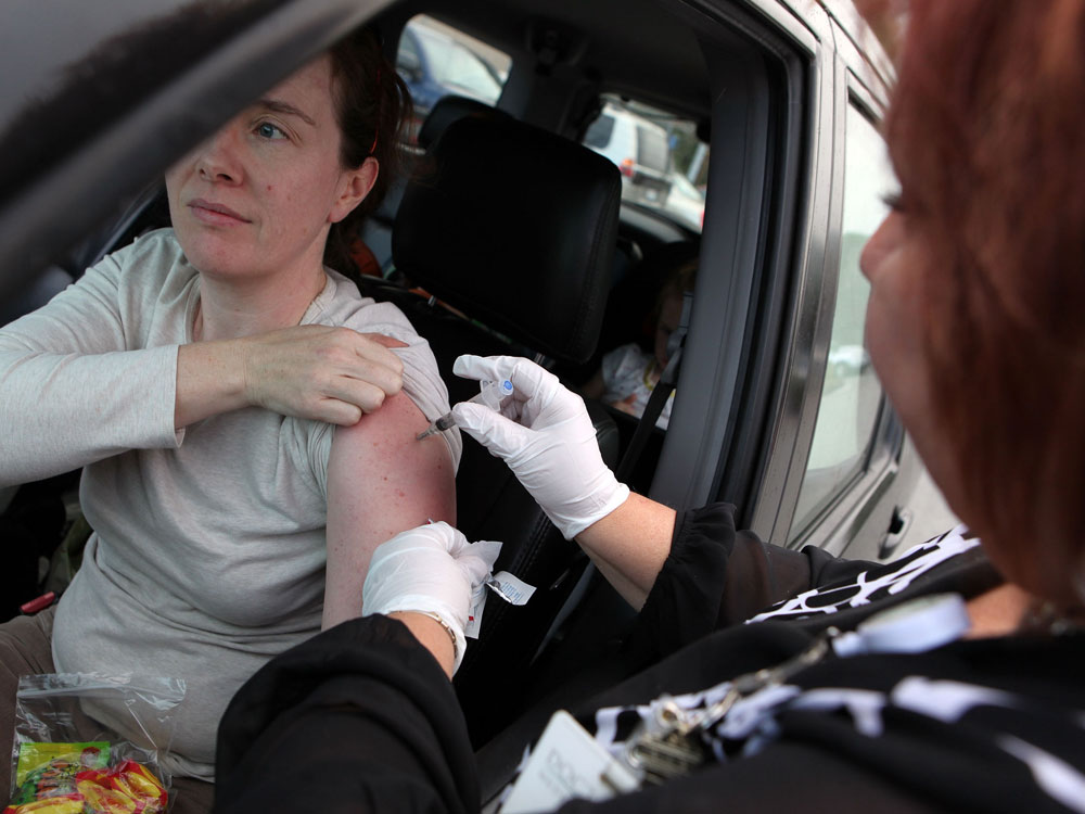 A woman getting an H1N1 vaccine in her car.