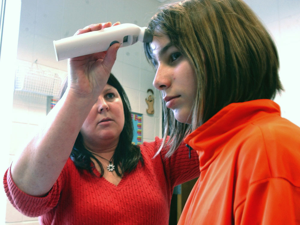 A health aide takes the temperature of a school girl in Wisconsin.