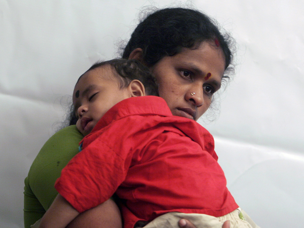Indian woman holds her baby who has pneumonia.