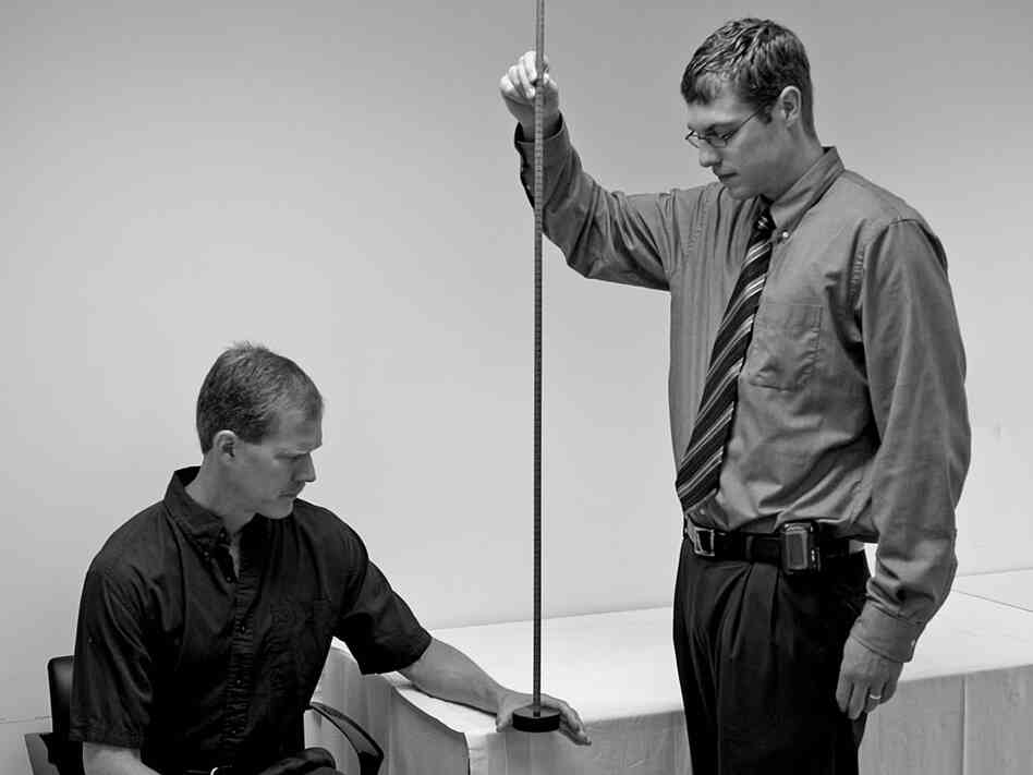 A researcher tests a subject's reaction time by having him catch a weighted stick.
