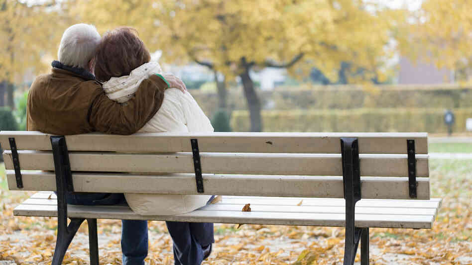 Older couple sitting on park bench.