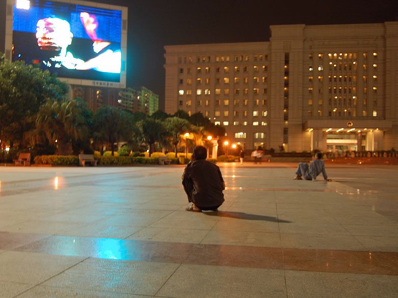 Chinese factory worker watches Jumbotron in town square