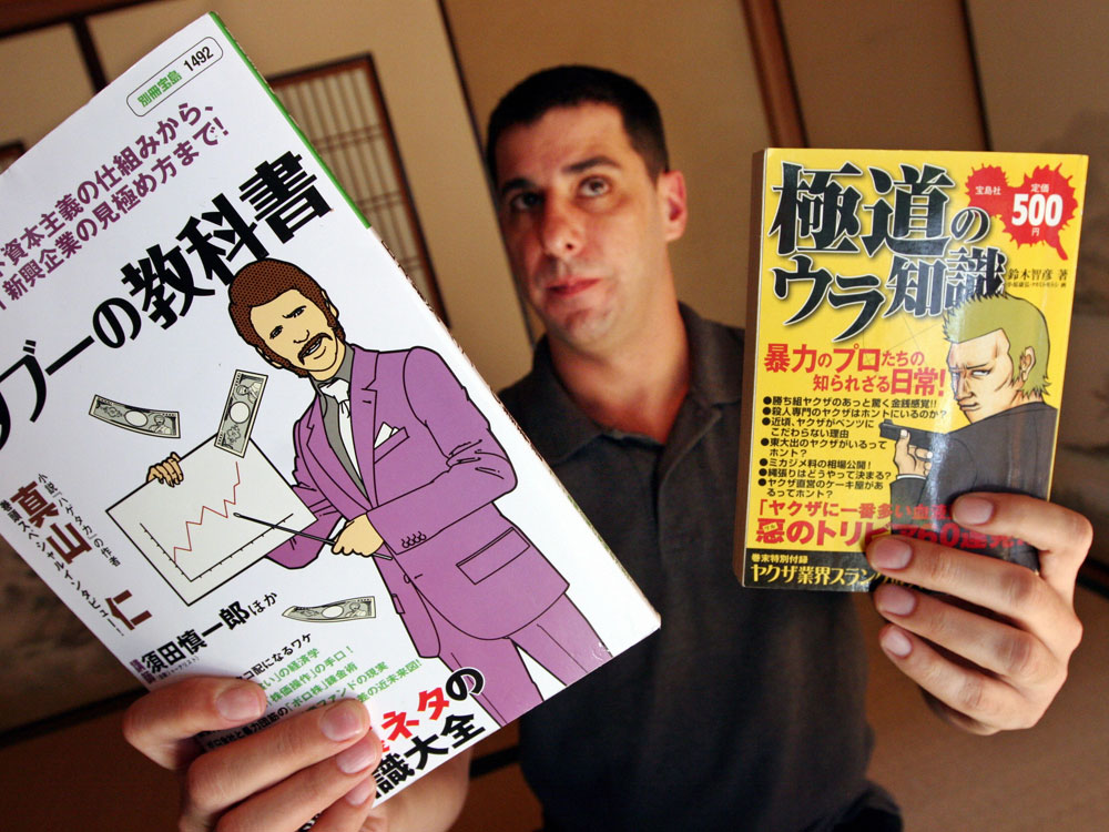 Jake Adelstein holds up manga magazines based on the yakuza