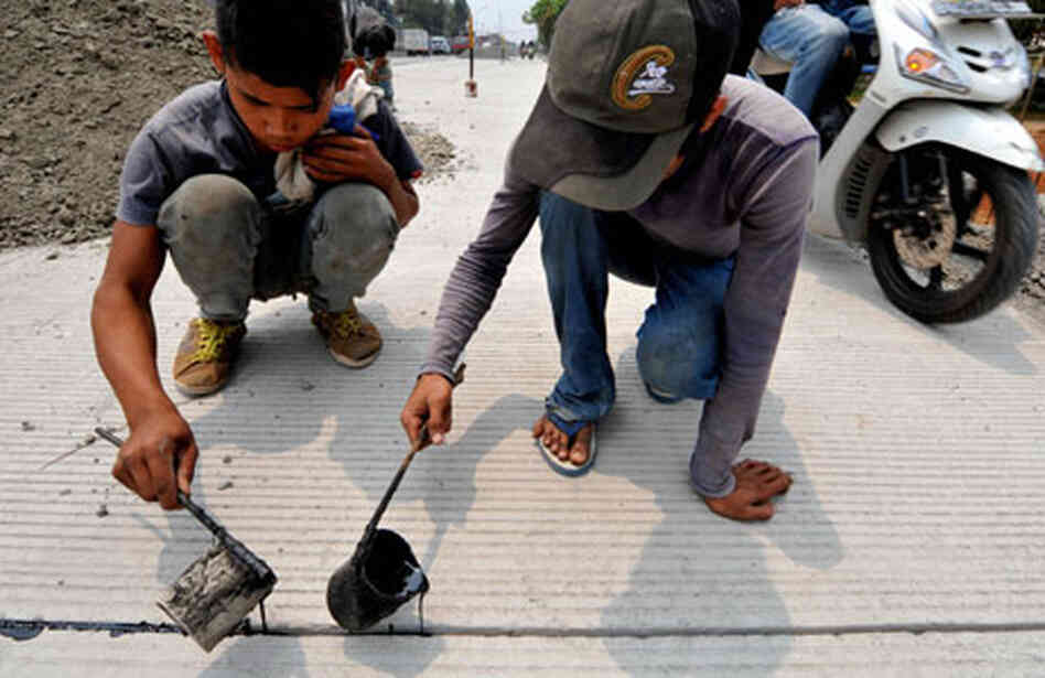 Young workers fix a road in Indonesia. Young workers fix a road in Indonesia.