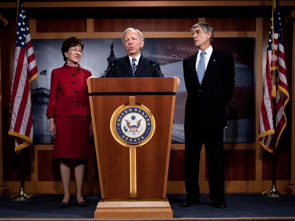 Sen. Susan Collins (R-ME) (L) and Sen. Mark Udall (D-CO) (R) listen to Sen. Joseph Lieberman (I-CT) speak.
