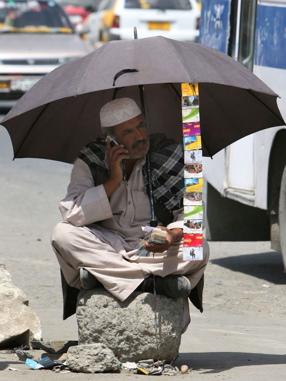 An Afghan man talks on the his cell phone as he sells credit cards along a main road in Kabul, Afghanistan, Monday, Aug 25, 2008. (AP Photo/Musadeq Sadeq)