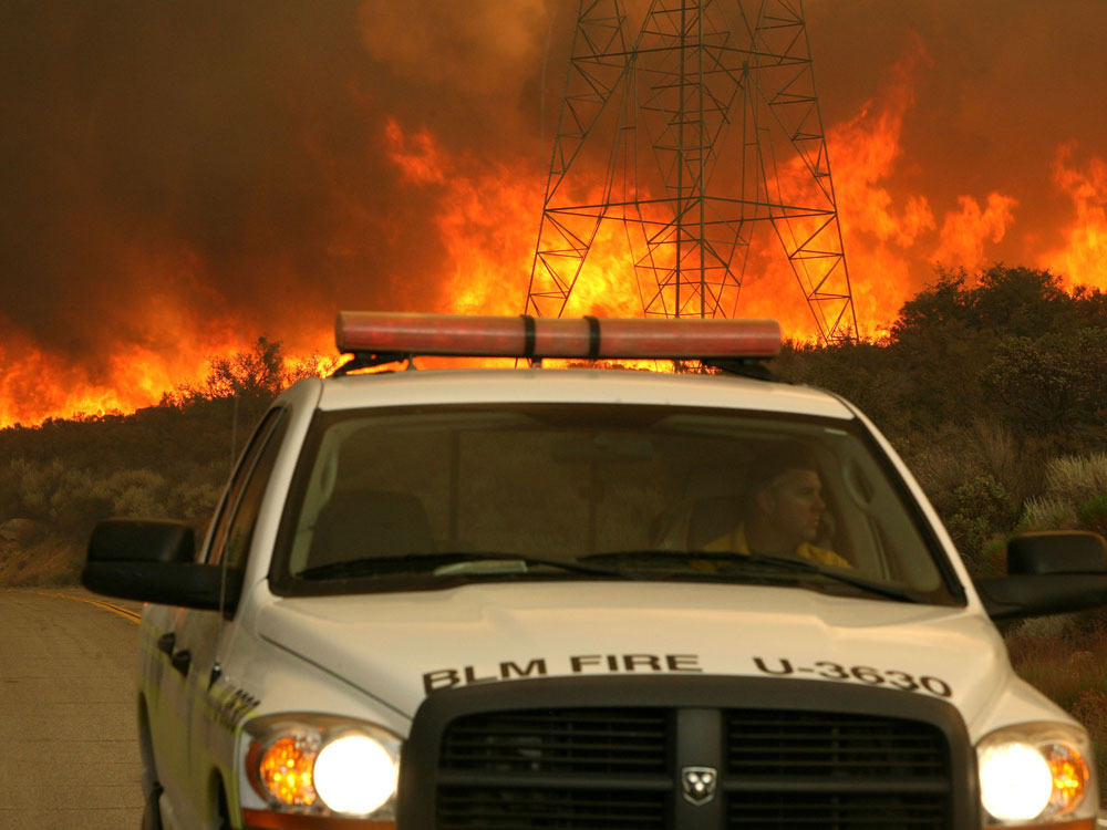 ACTON, Calif. -- AUGUST 30: A fire fighter drives away from a wall of flames. The out of control Station Fire, which broke out Wednesday afternoon near a ranger station and the Angeles Crest Highway above La Canada Flintridge, has forced thousands of evacuations as nearly 10,000 homes are threatened. (Photo by Justin Sullivan/Getty Images)