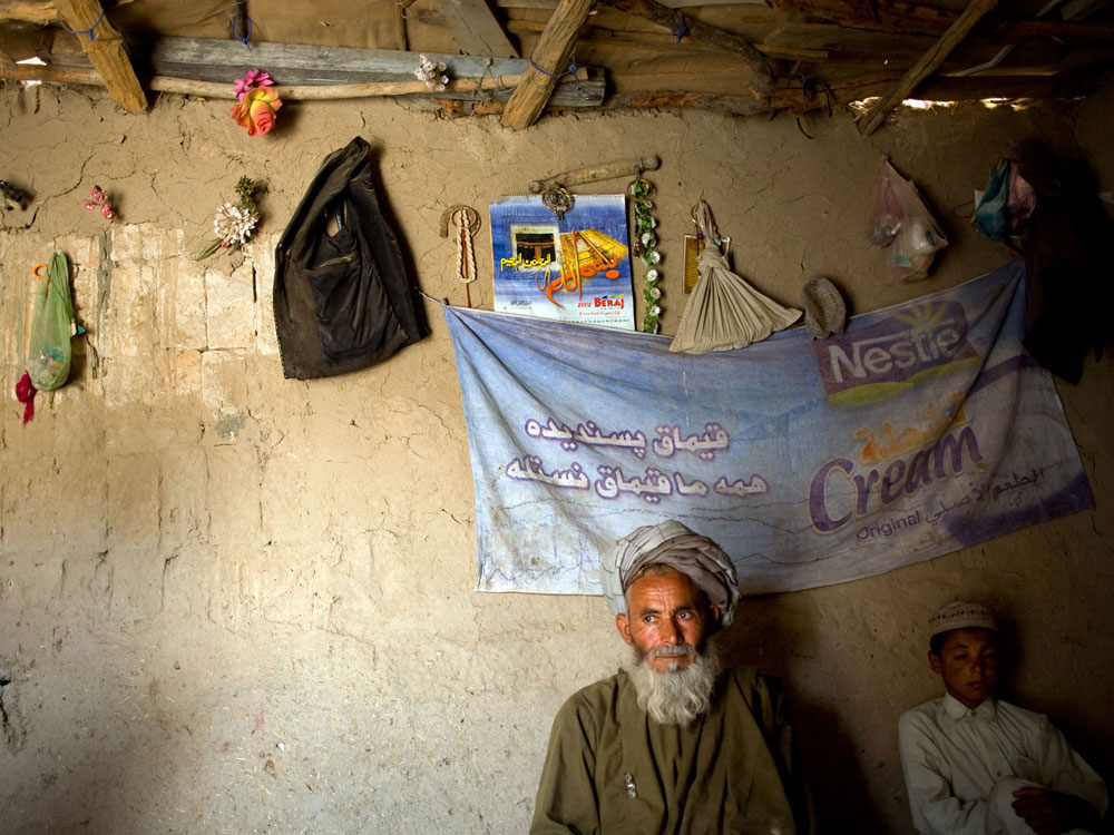 Khalik Daad, 60, sits with his son Wali, 14, in their small mud hut in Kandahar. Daad's 10-year-old daughter Jamila was killed instantly on Aug. 20 when a rocket hit the building next door and shrapnel fell into the hut where the family was preparing lunch. Daad's wife and another young daughter were also injured and taken to the hospital. (Holly Pickett for NPR)