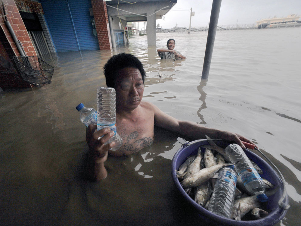   Local residents receives bottled water as they catch fish brought in by floodwaters caused by Typhoon Morakot in Chiatung, Pingtung county, in southern Taiwan, on August 9, 2009.  (Sam Yeh/AFP/Getty Images)