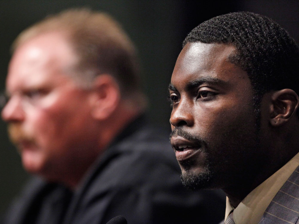 Michael Vick is along with seen Philadelphia Eagles head coach Andy Reid during a news conference in Philadelphia, Friday, Aug. 14, 2009. Vick is back in the NFL, landing a job with the Philadelphia Eagles. (AP Photo/Matt Rourke)