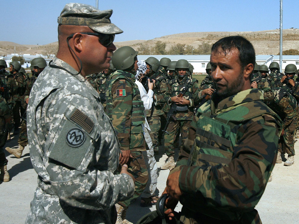American Army instructor speaks with Afghan soldier.