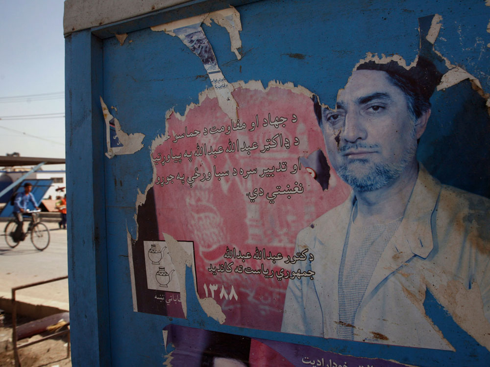 An Afghan boy rides a bicycle as torn and defaced election poster of Abdullah Abdullah, former Afghan foreign minister who runs against President Hamid Karzai in last August's vote, is seen on a wall in Kabul, Afghanistan, Tuesday, Oct. 20, 2009. (AP Photo/Musadeq Sadeq )