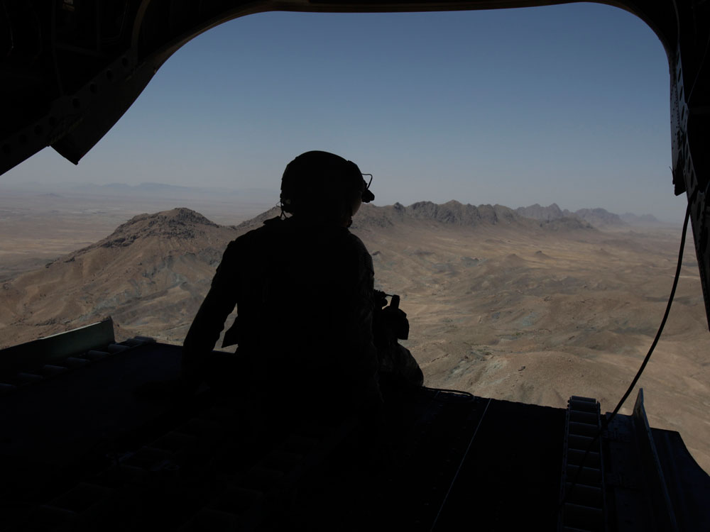 Sgt. Lee Brown Jr., the tail gunner on a Chinook helicopter with Bravo Company, 3rd Battallion of the 82nd Combat Aviation Brigade, sits behind his weapon as the aircraft passes over mountains on its way to the Zabul province of Afghanistan to transport supplies and troops to different forward operating bases there Wednesday, June 17, 2009. (AP Photo/Julie Jacobson)