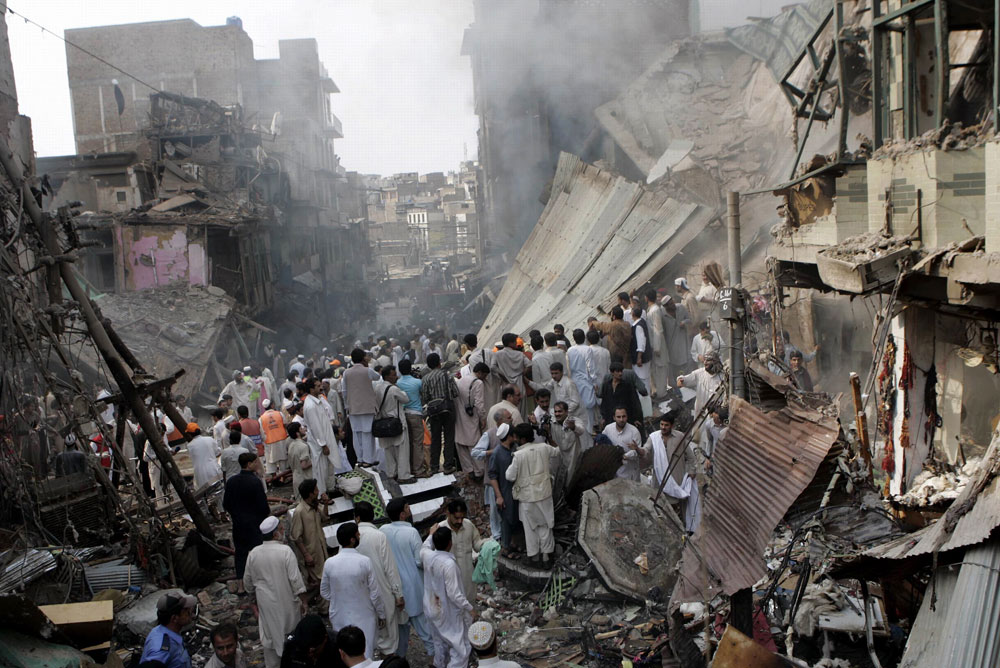 People gather at the site of an explosion in Peshawar, Pakistan on Wednesday Oct. 28, 2009. A car bomb tore through a busy market. (AP Photo/Mohammad Sajjad)