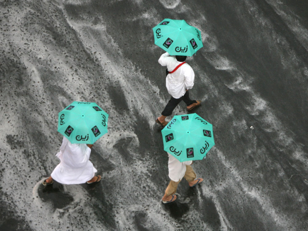 Muslim pilgrims run for cover as heavy rain streams down a road in the holy city of Mecca on November 25, 2009. An estimated 2.5 million Muslims have converged on Mecca for the annual hajj pilgrimage, as workers toil round the clock to complete construction projects designed to avoid deadly stampedes. (Photo by Mahmud Hams/AFP/Getty Images) 