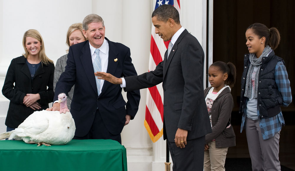 President Barack Obama waves his hand as he pardons a turkey named Courage, alongside his daughters Malia (R) and Sasha (2nd R), and National Turkey Federation Chairman Walter Pelletier (3rd L), during the annual turkey pardoning ceremony for Thanksgiving on the North Portico of the White House in Washington, DC, on November 25, 2009. (Photo by Saul Loeb/AFP/Getty Images)  