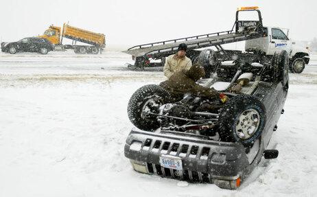 Brent Levander watches as his brother, Brian, hooks a chain to the bottom of a vehicle as they work to right it after a driver lost control and rolled into a ditch while traveling on U.S. Highway 281 north of Hastings, Neb. Wednesday, Dec. 23, 2009. Freezing drizzle combined with heavy snow has made travel dangerous in south central Nebraska. (AP Photo/Hastings Tribune, Brent McCown)