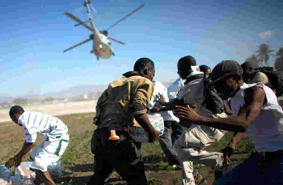 Men scramble Saturday to grab some of the relief supplies delivered by a U.S. military helicopter. (