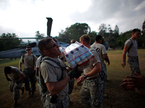 U.S. Army soldiers from the 82nd Airborne pass relief from a Navy helicopter supplies at a golf club on the hills above the capital of Port-au-Prince Haiti, Wednesday January 20, 2010. (David Gilkey/NPR)