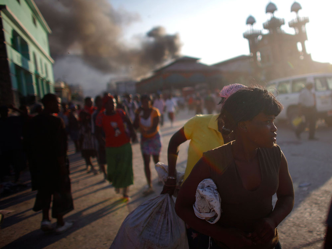 Haitians scatter as police fire shots in the street to try and disperse crowds from looting in the c