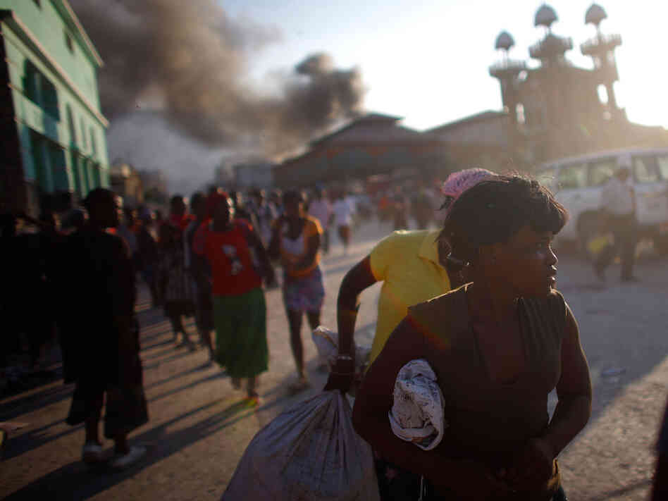 Haitians scatter as police fire shots in the street to try and disperse crowds from looting in the c